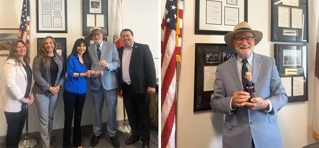 Senator John Laird proudly displaying his California Community Colleges Legislative Champion of the Year award and a personalized California Arts Council bobblehead.
