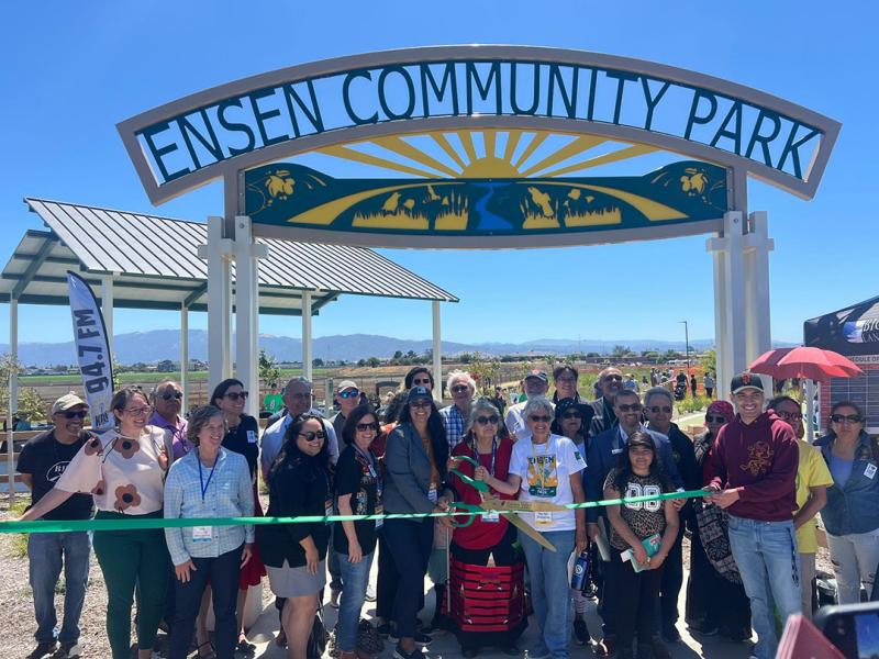 Sen. Laird with nonprofit leaders and constituents cutting a giant green ribbon